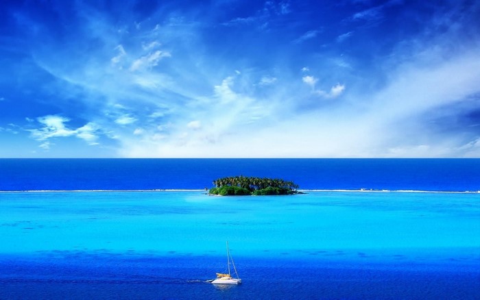Island in the ocean with a sailboat