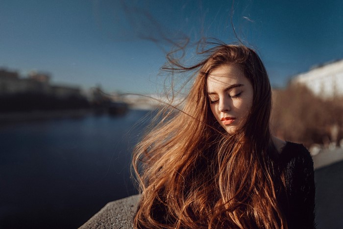Woman with long hair in the wind by the river