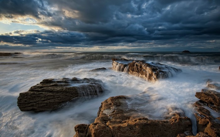 Dramatic Rocky Shore with Ocean Waves at Dusk