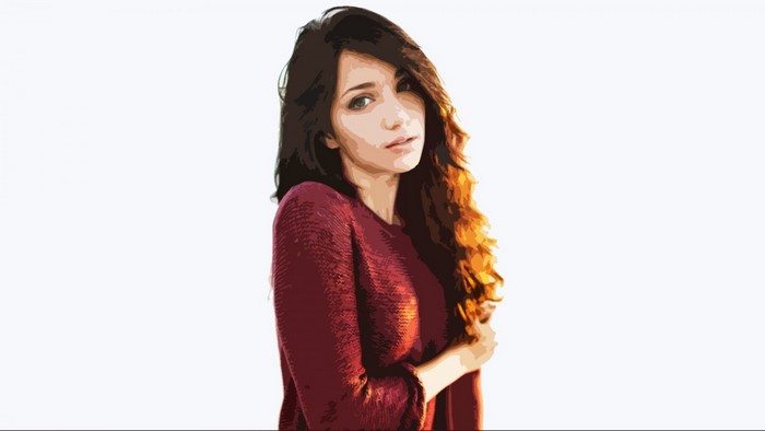 Emily Rudd with long brown hair wearing a red sweater