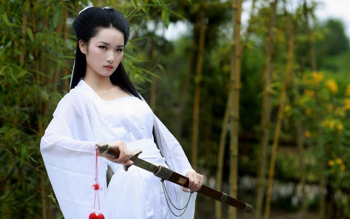 Woman in white dress holding a sword outdoors
