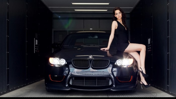 Woman in black dress sitting on a black BMW M3