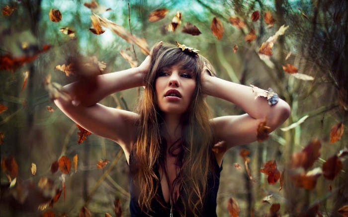 Woman with hands on head in autumn forest