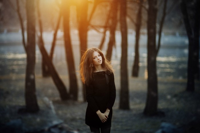Woman in black dress in forest at sunset
