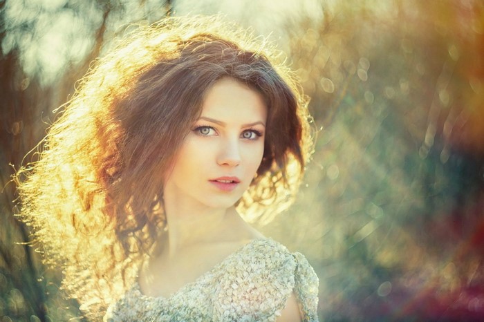Portrait of a young woman with long brown hair in sunlight