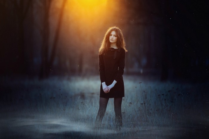 Woman in black dress in sunlit forest