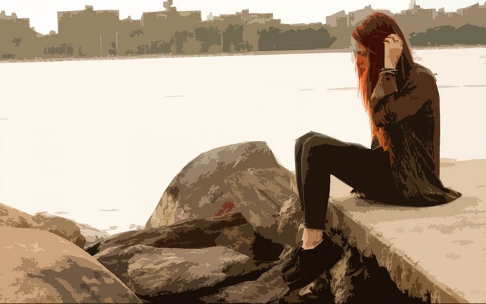 Woman sitting on rocks by the water