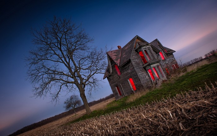 Abandoned house with red windows at dusk
