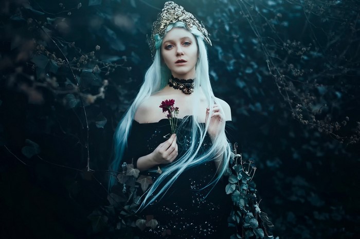 Woman with pale blue hair and crown in dark forest