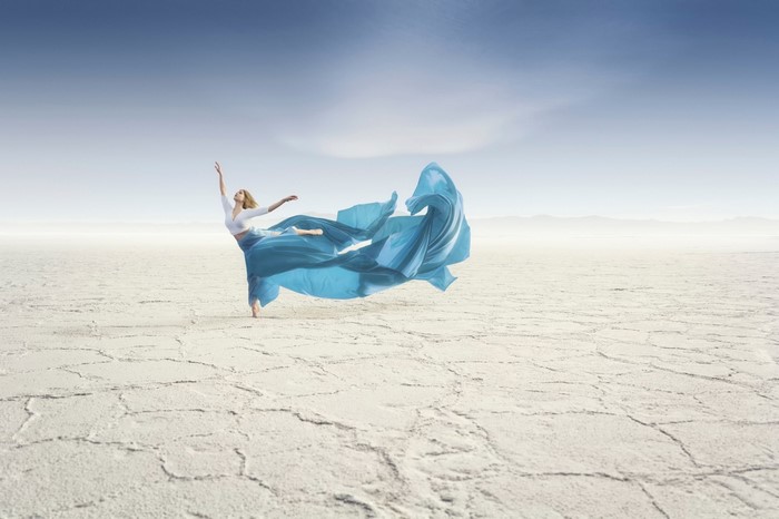 Woman dancing in a blue dress in a dry landscape