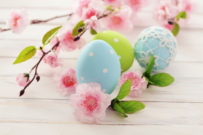 Easter eggs and pink cherry blossoms on a wooden surface