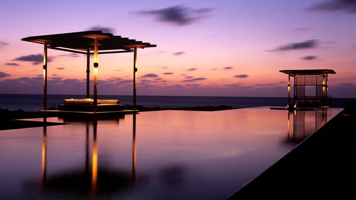 Infinity pool at sunset with gazebos overlooking the ocean