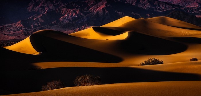 Golden sand dunes and mountains at sunset