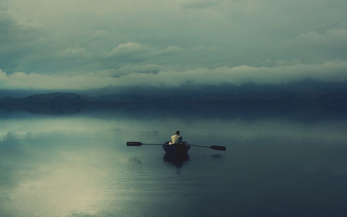 Person rowing a boat on a misty lake at dawn