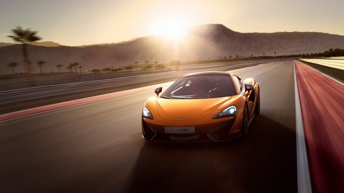 Orange McLaren 570S driving on a race track at sunset