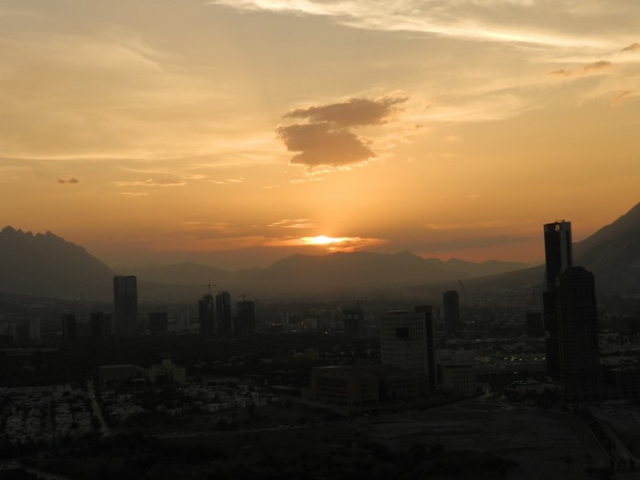 Cityscape at sunset with mountains and haze