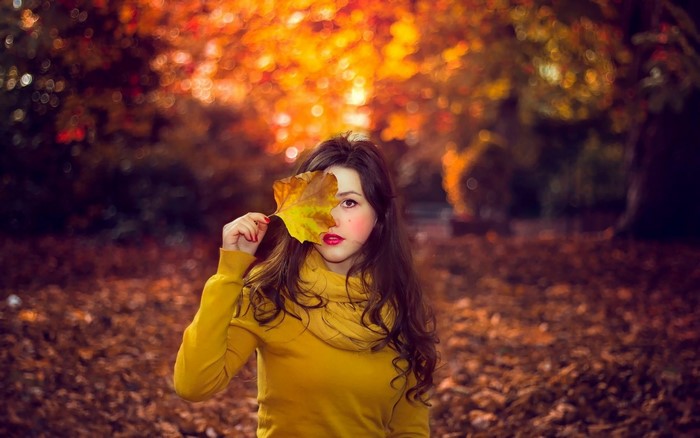 Woman holding a yellow leaf in autumn