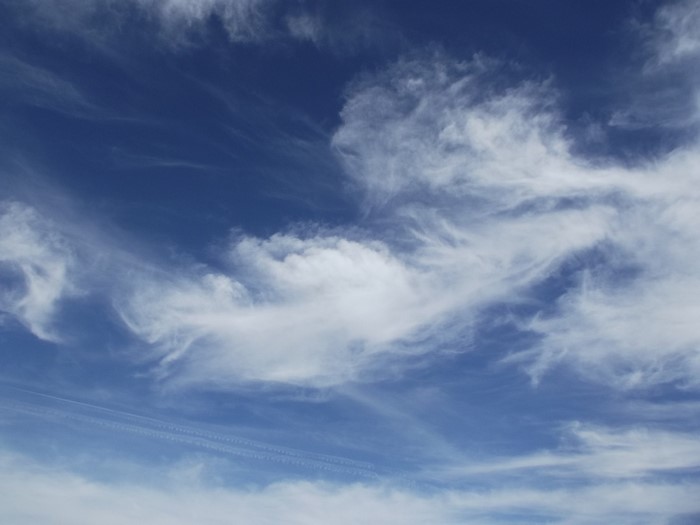 Blue sky with wispy white clouds and contrails