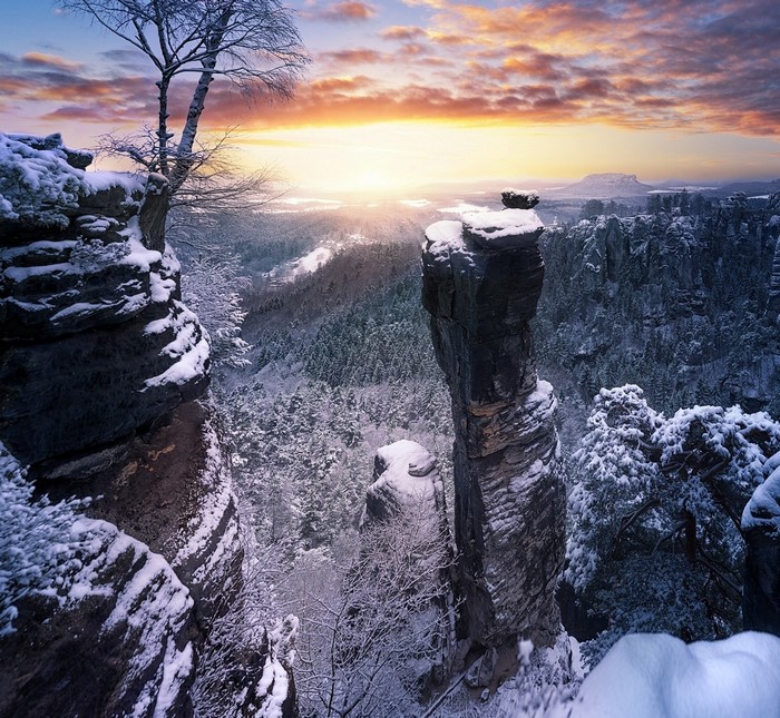 Snowy mountain landscape at sunrise with rock formations