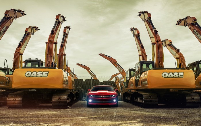 Red Chevrolet Camaro parked between CASE excavators