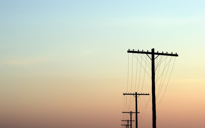 Silhouette of utility poles against a sunset sky