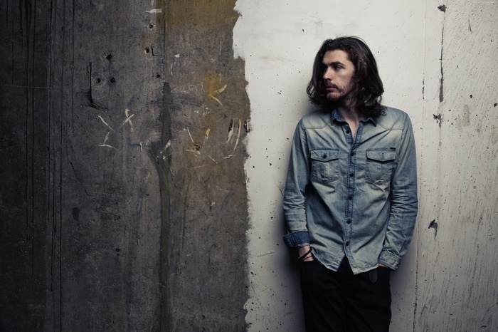Hozier standing against a textured wall