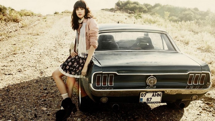 Woman leaning on a vintage Ford Mustang in Turkey