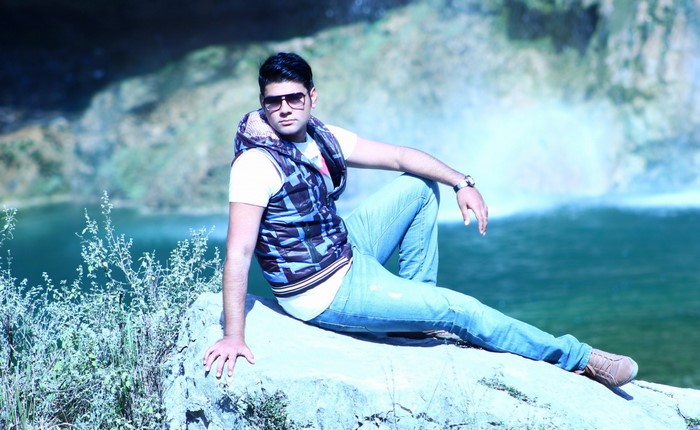 Man in sunglasses and vest sitting by a lake