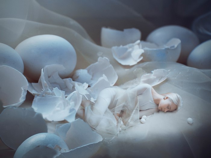 Woman sleeping among broken eggs and fabric