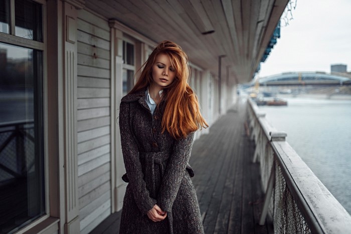 Woman with red hair wearing a coat on a pier