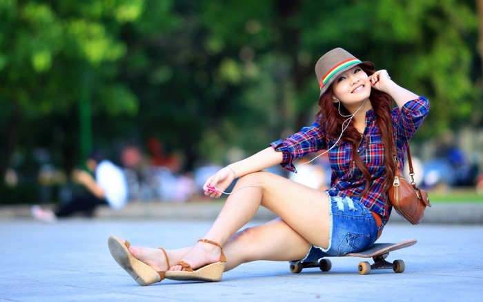 Asian woman wearing hat and plaid shirt on skateboard