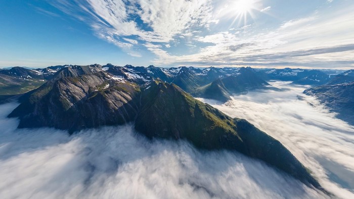 Mountains covered in mist and snow under a bright sun