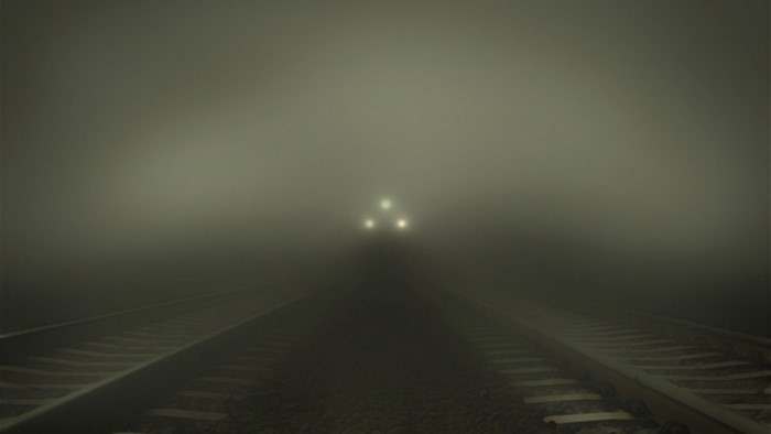 Train approaching in thick fog on railway tracks