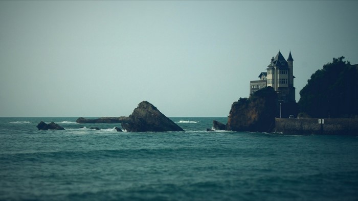 House on a cliff overlooking the sea with rocks