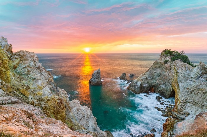 Sunset over rocky coast with sea stacks and turquoise water