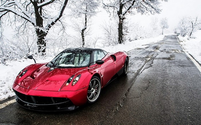 Red Pagani Huayra sports car on a snowy road