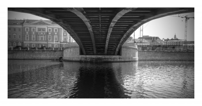 Under a bridge with a river and buildings