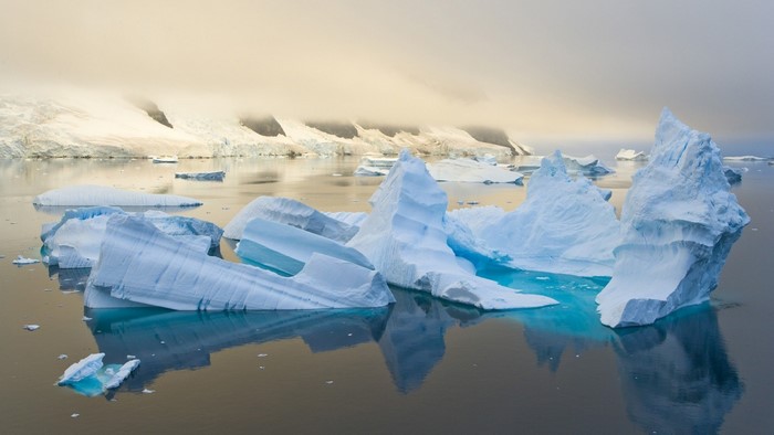 Icebergs floating in the Arctic Ocean with misty mountains