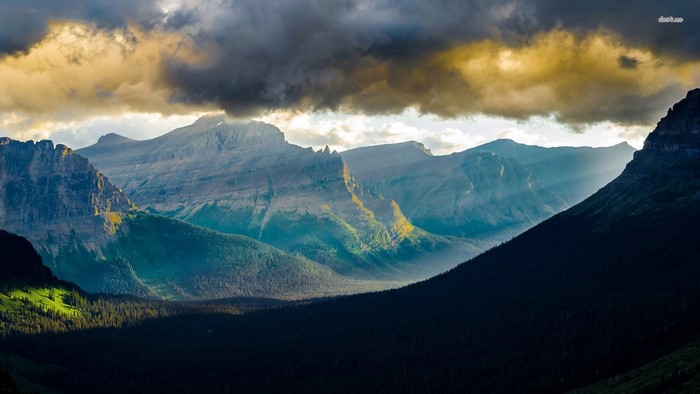Mountain range with sunbeams through clouds at dawn