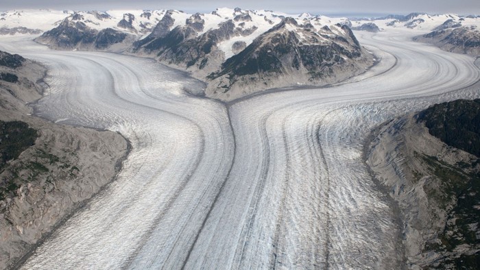 Aerial view of a vast glacier flowing through mountains