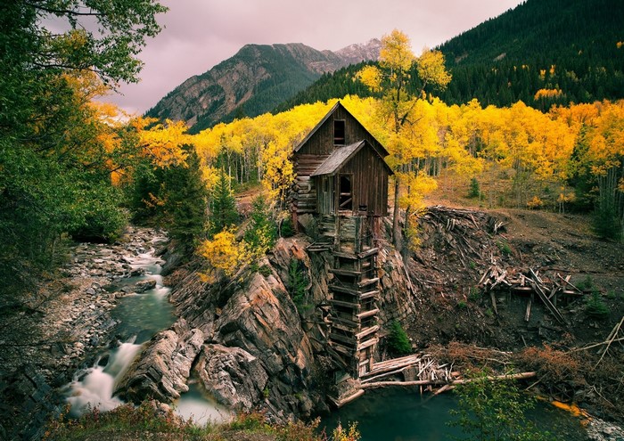 Old wooden mill by a river in autumn mountains