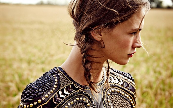 Woman with braided hair and ornate top in field