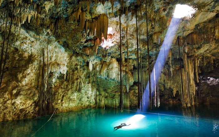 Person swimming in a sunlit cave cenote