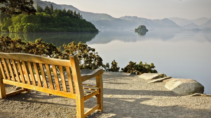 Wooden bench overlooking a calm lake and mountains