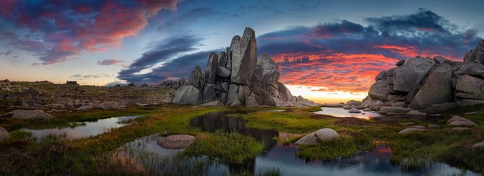 Panoramic sunset over rocky landscape with water and clouds