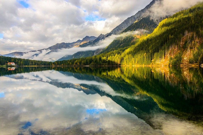 Mountain lake with forest and clouds reflection