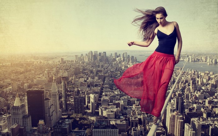 Woman in red skirt on tightrope over New York City