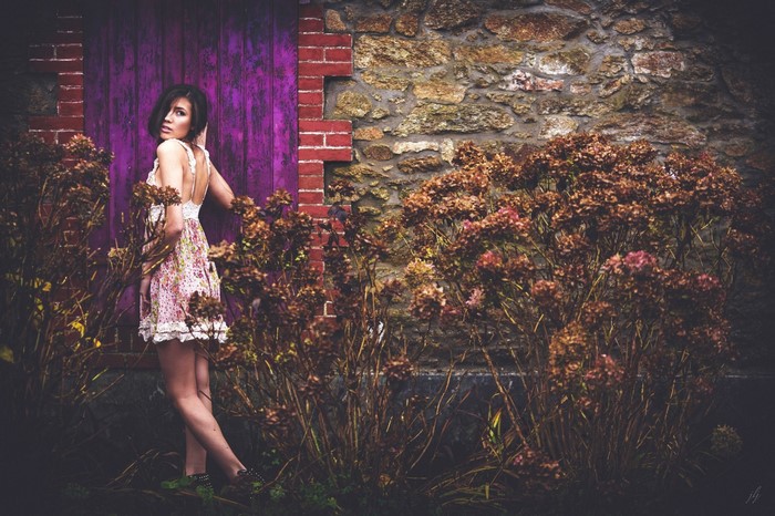 Woman in floral dress by purple door and stone wall