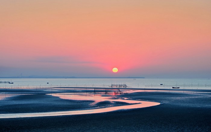 Sunset over the sea with a winding river on the shore