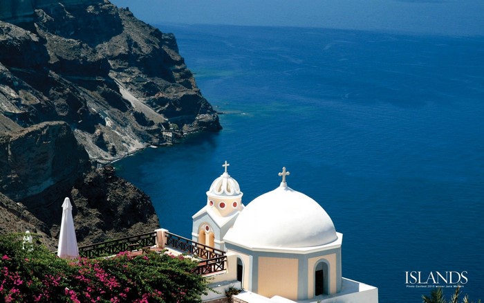 White domed churches on Santorini coast overlooking the Aegean Sea